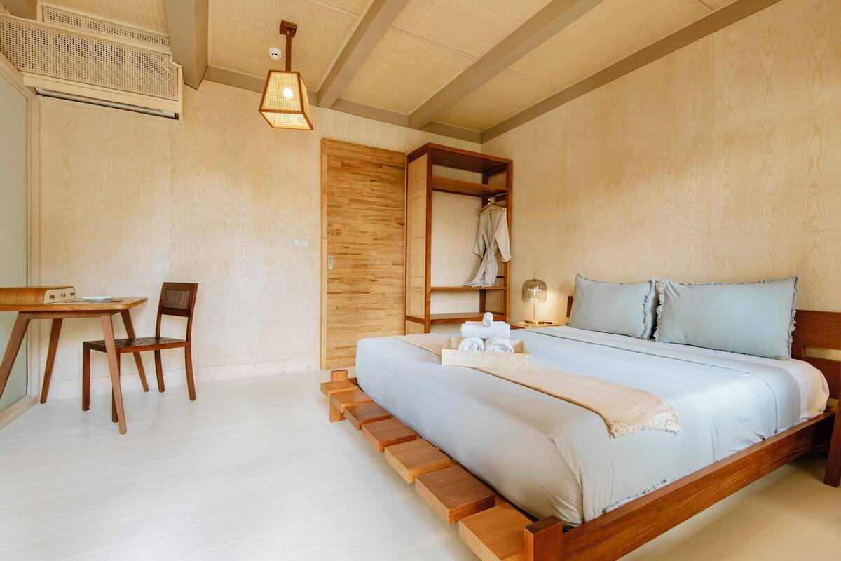 A bedroom with a wooden bed, a wooden desk, and a chair.