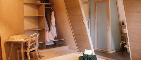 Ein Schlafzimmer mit einem Bett, einem Schreibtisch und einem Stuhl. Es gibt einen Holzschrank und einen kleinen Tisch mit einer Lampe.
