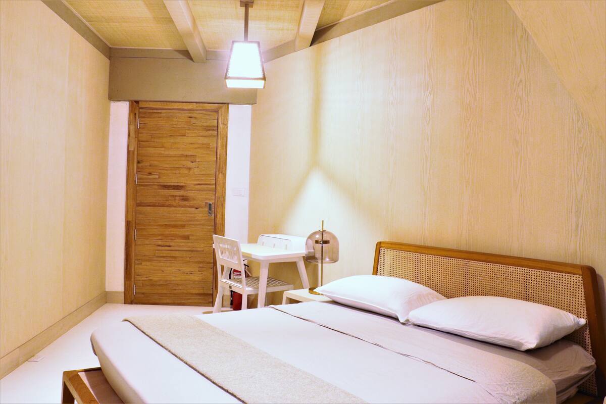 A bedroom with a bed, a desk, and a chair.