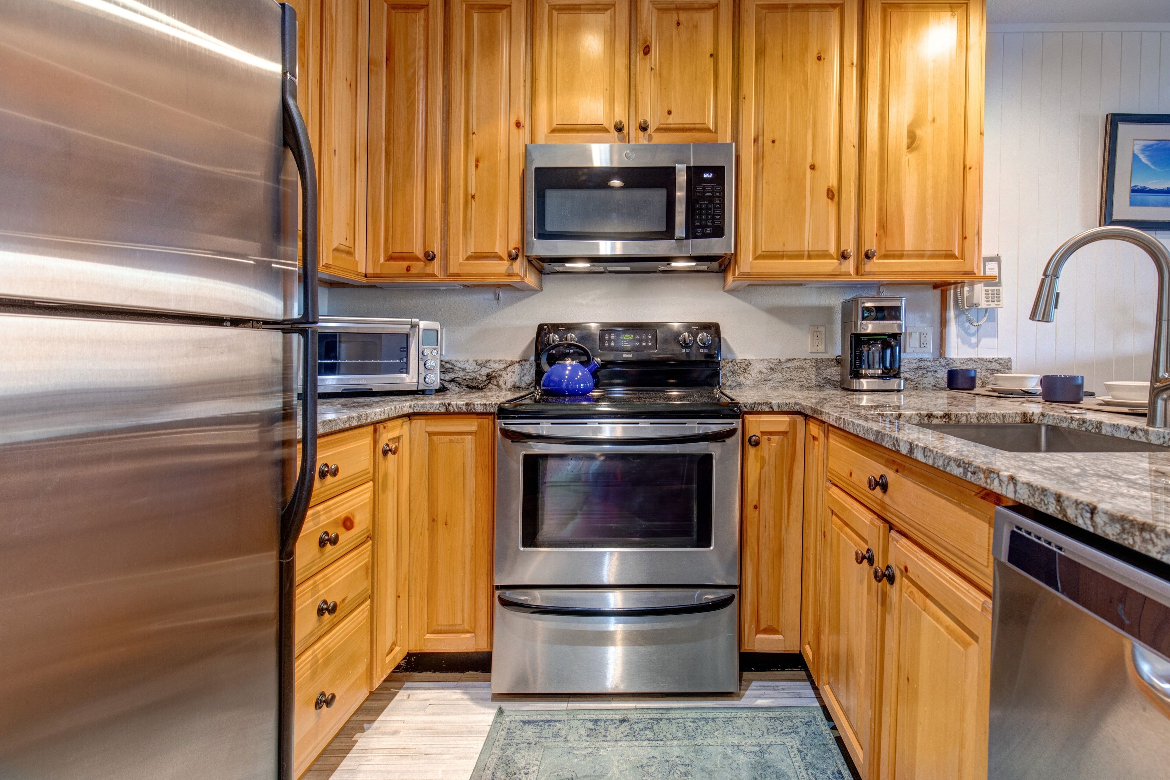 A kitchen with stainless steel appliances, wooden cabinets, granite countertops, and a built-in oven.