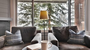 A cozy seating area with a sofa, two pillows, a coffee mug, and a book on a small round table.