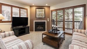 A living room with a fireplace, a television, and a sofa. - Snow Flower 111 2 Bedroom Condo by RedAwning (Park City)