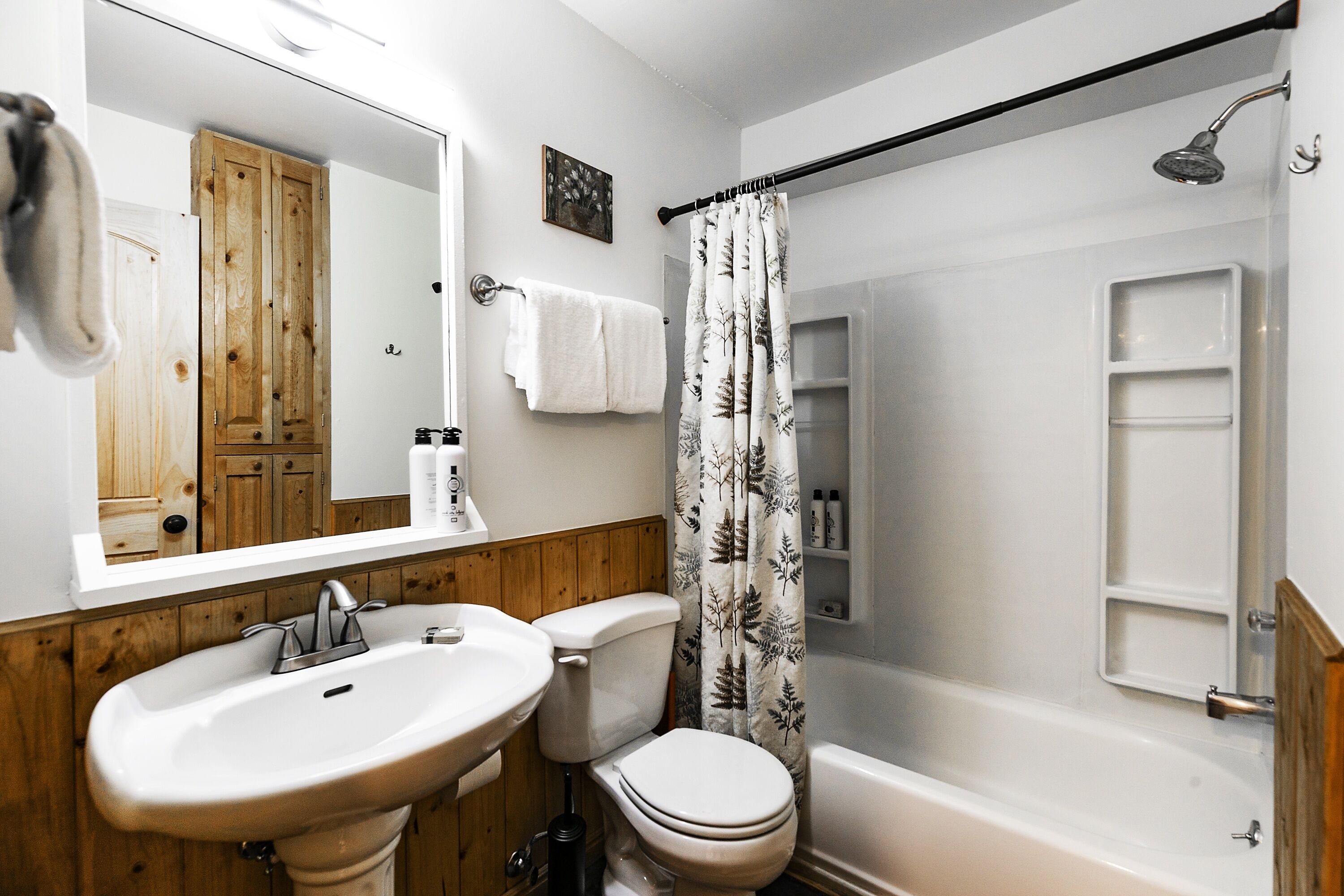 Une salle de bain avec un meuble-lavabo en bois, un lavabo, des toilettes et une baignoire.
