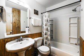 A bathroom with a wooden vanity, a sink, a toilet, and a bathtub.