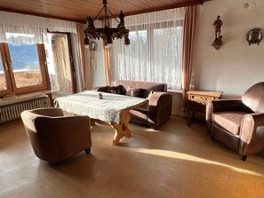 A cozy living room with a wooden table, two sofas, and a leather armchair.