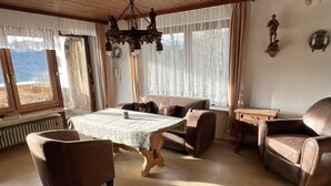A cozy living room with a wooden table, two sofas, and a leather armchair.