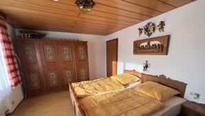 A bedroom with a wooden bed, a wardrobe, and a ceiling light fixture.