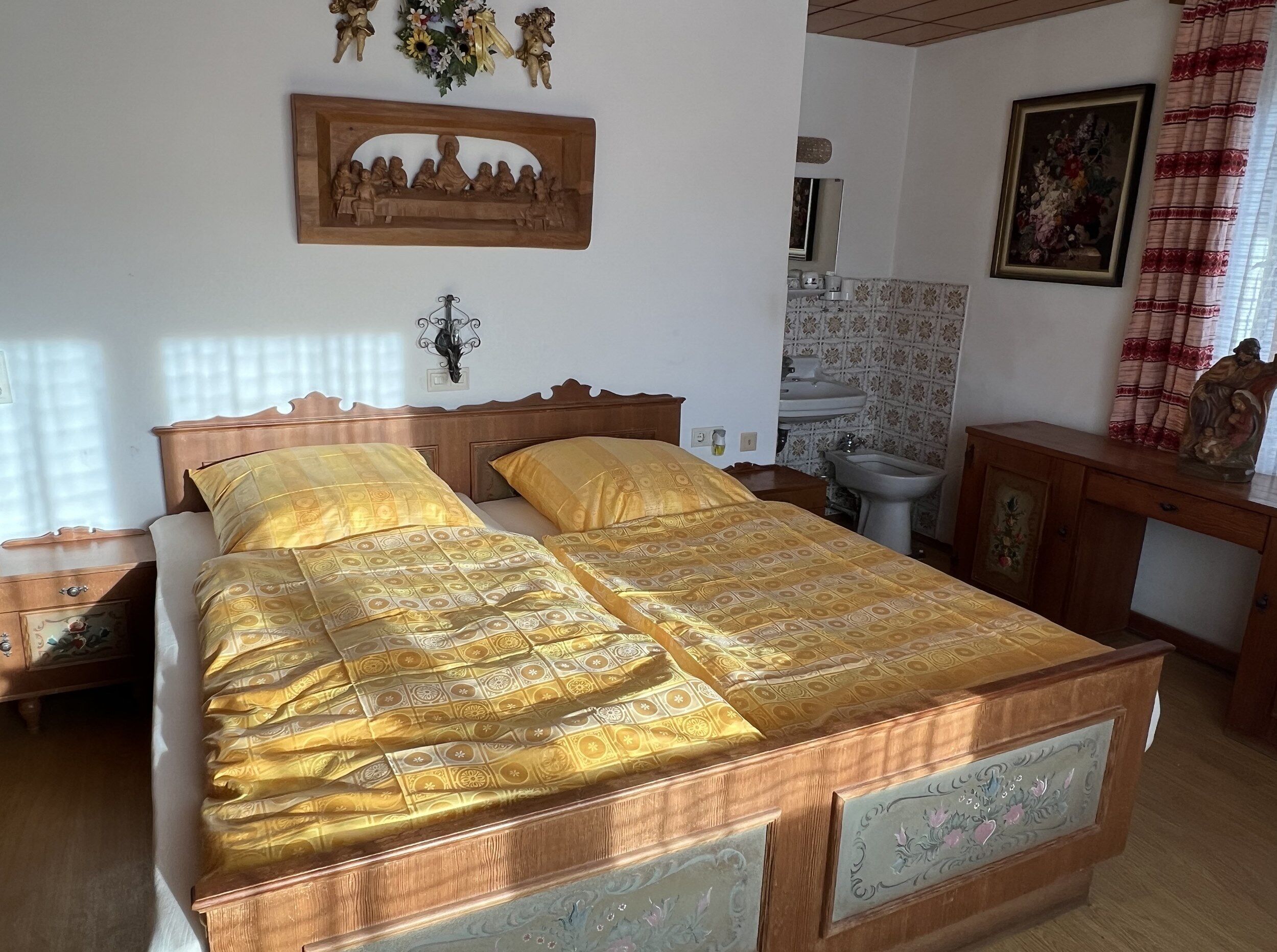 A double bed with a wooden frame and a floral-patterned bedspread.