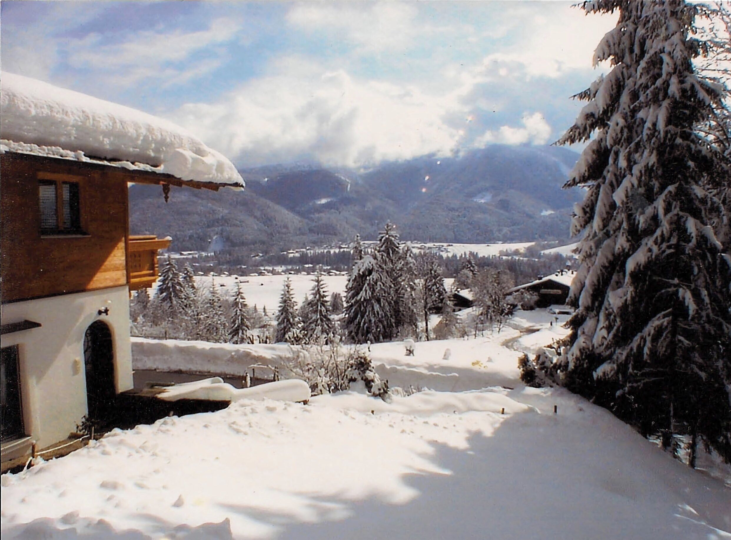 A snow-covered landscape with a wooden house and snow-laden trees.