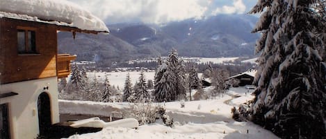 A snow-covered landscape with a wooden house and snow-laden trees.