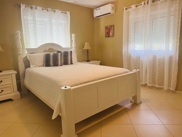 Une chambre à coucher avec un lit, des tables de chevet, une lampe et des rideaux.