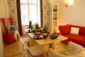 Ein gemütliches Wohnzimmer mit einem Holzesstisch, einem roten Sofa und einem Fernseher auf einem roten Schrank.