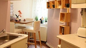 Une cuisine compacte dotée de meubles en bois, d’un évier et d’un coin repas comprenant une chaise et une table.