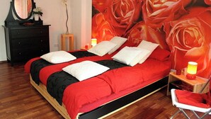 Un lit avec une literie rouge et noire, des oreillers blancs et une tête de lit en bois.