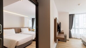 Una habitación de hotel moderna con dos camas, un televisor de pantalla plana y piso de madera.