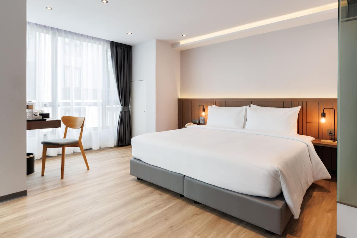 A modern hotel room with a large bed, a desk, and a chair.