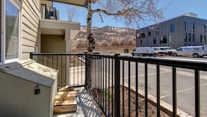 A balcony with a view of a modern building and parked vehicles in the background.