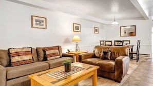 A cozy living room with a sofa set, a wooden coffee table, and a dining area with a table and chairs.