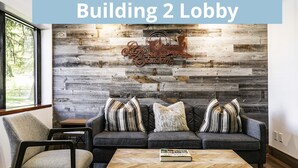 A modern living room with a grey sofa, striped pillows, and a rustic wall with a 'Park Station' sign. - Park Station 214-1 1 Bedroom Condo by RedAwning (Park City)
