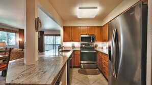 A kitchen with wooden cabinets, a stainless steel refrigerator, a microwave, and a built-in oven. - Snow Flower 148 2 Bedroom Condo by RedAwning (Park City)