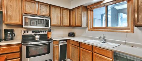 A kitchen with wooden cabinets, stainless steel appliances, a window, and a sink.