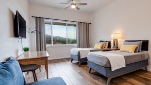Habitación de hotel con dos camas, un escritorio, un televisor y una ventana con cortinas.