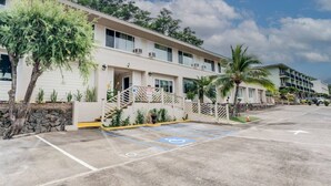 Un hotel con estacionamiento, un corredor cubierto y un edificio de varios pisos con balcones.