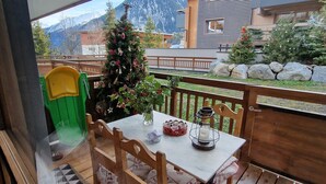 A wooden deck with a table and chairs, a Christmas tree, and a mountain view. - Direct access to the slopes & village center; parking included. South-facing terrace. Cozy & comfortable 3* (Courchevel)