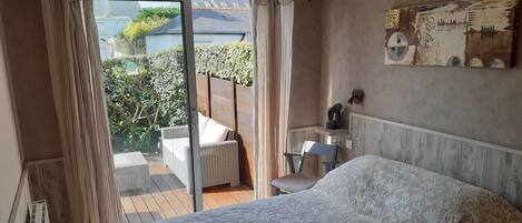 A bedroom with a large bed, a chair, a desk, and a view of the outdoors.