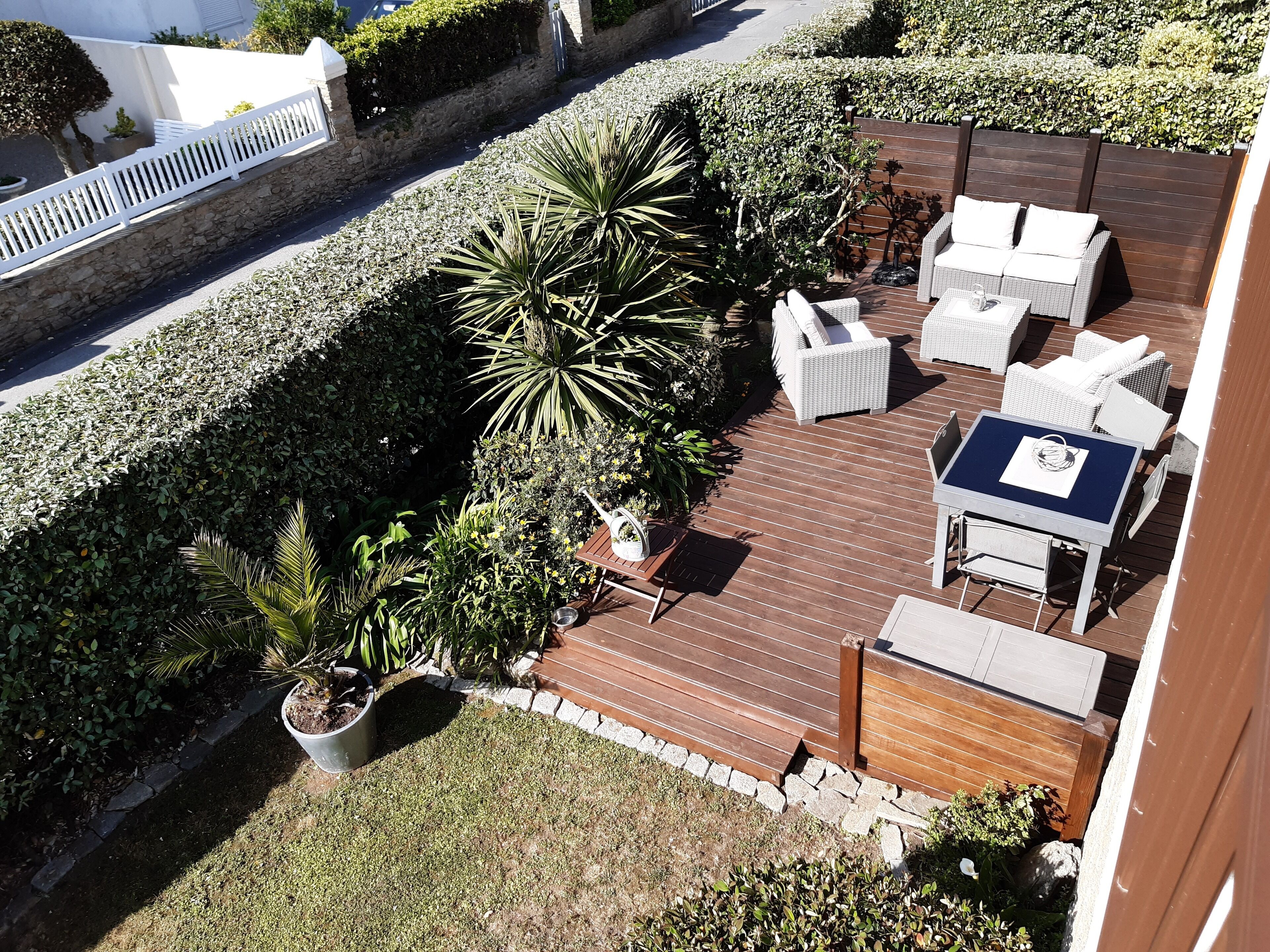 Une terrasse avec des meubles d’extérieur, une petite table et des plantes en pot.