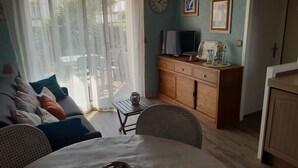 Un salon comprenant un canapé, une table à manger et un téléviseur posé sur un meuble en bois.