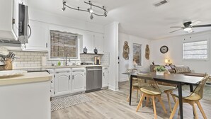 Een moderne keuken met witte kasten, een inbouwoven en een eethoek met een tafel en stoelen.