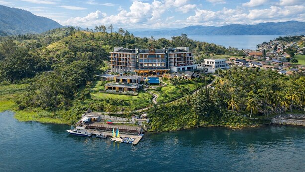 Un resort con diversi edifici, un molo con barche e una vegetazione rigogliosa che circonda un lago.