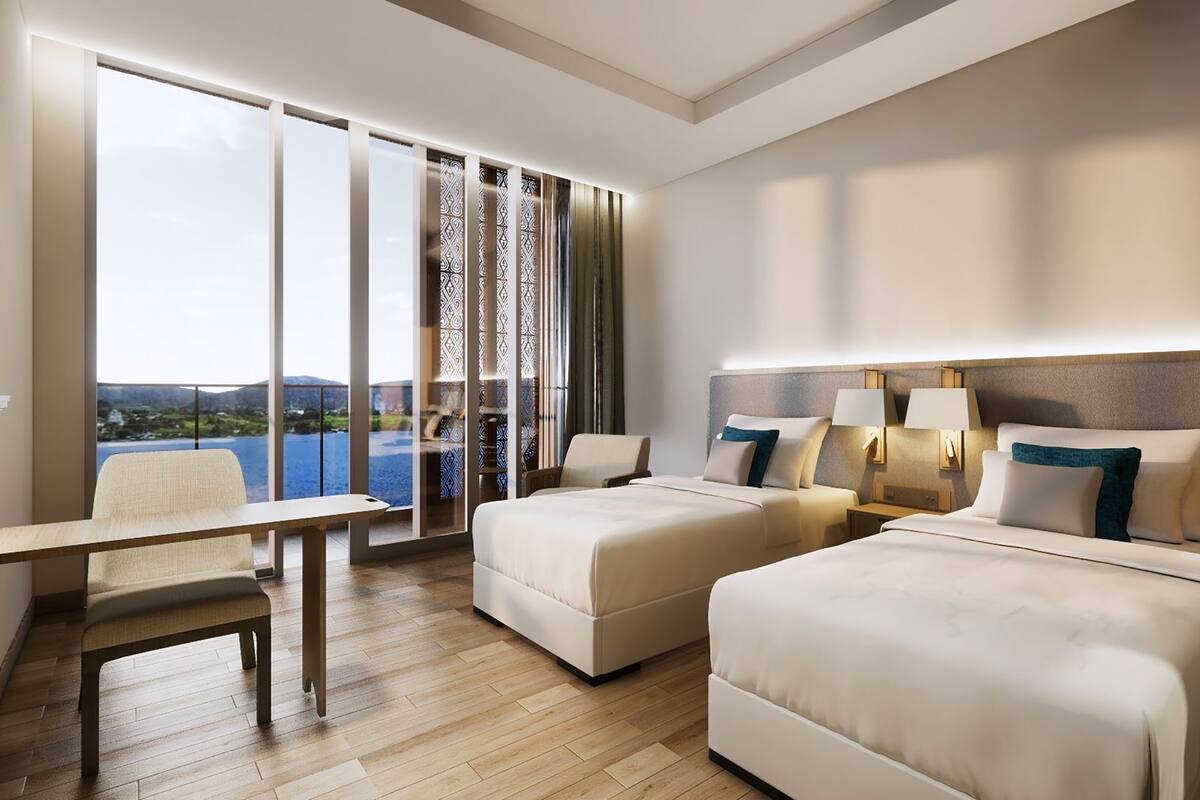 A hotel room with two beds, a desk, and a large window with a view.