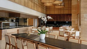 Un ristorante moderno con un tavolo centrale, sedie e un'orchidea in vaso.