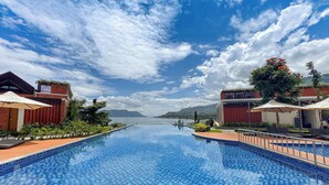 Una piscina con acqua blu piastrellata, circondata da edifici con facciate in mattoni rossi e vegetazione.