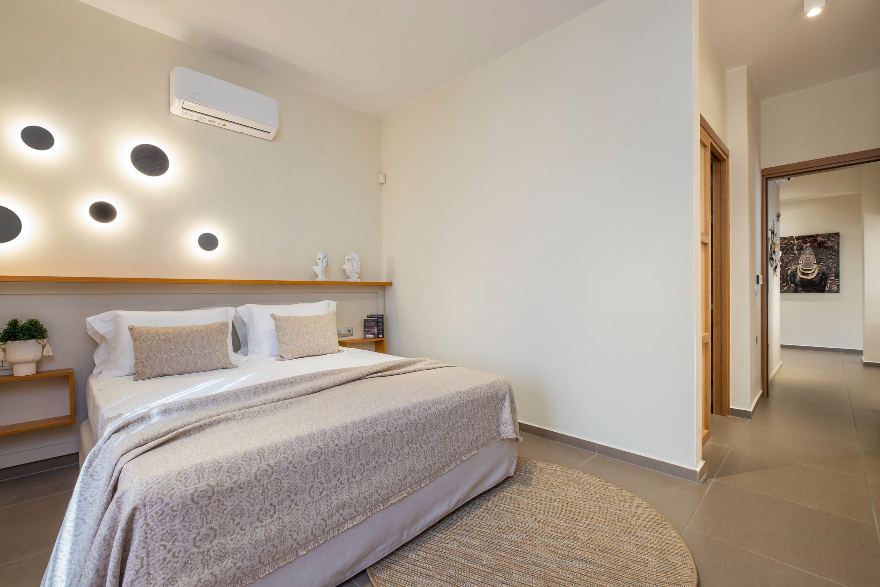 Un dormitorio moderno con una cama grande, mesitas de noche, aire acondicionado integrado en la pared e iluminación empotrada.