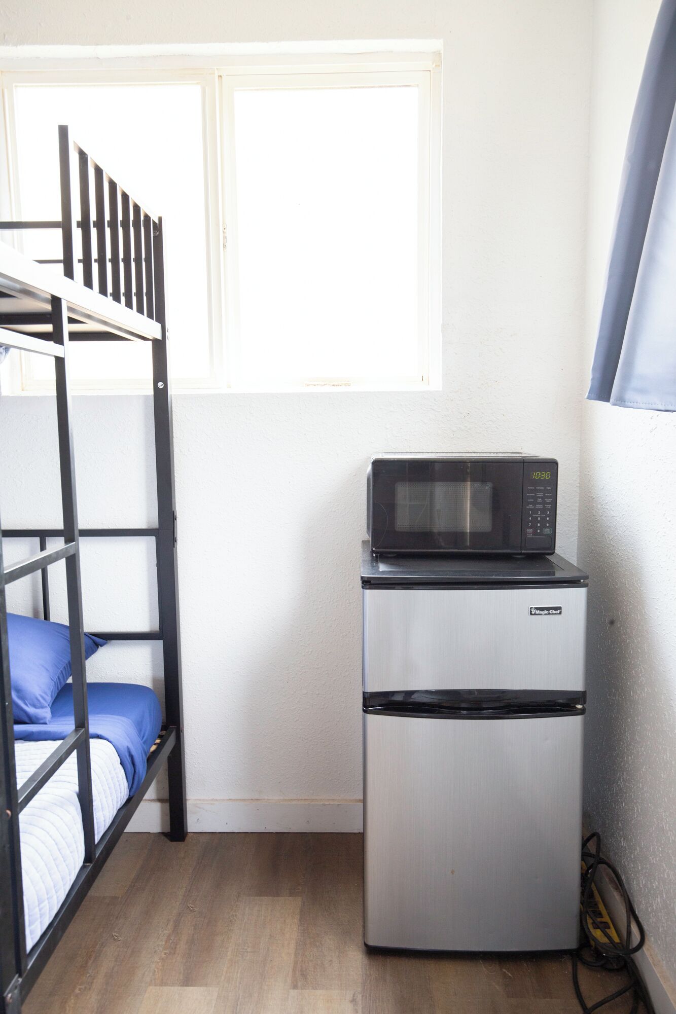 A compact room with a bunk bed, a microwave, and a refrigerator.