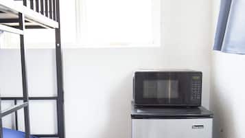 Une petite chambre équipée d’un lit superposé, d’un four à micro-ondes et d’un réfrigérateur.