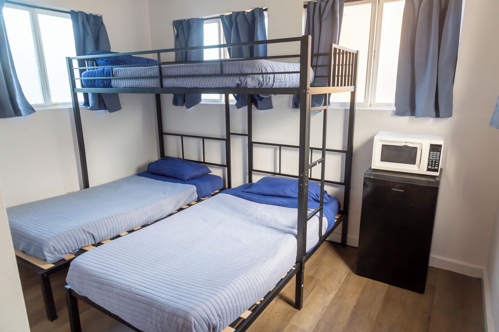 A dormitory room with bunk beds, a microwave, and a small refrigerator.