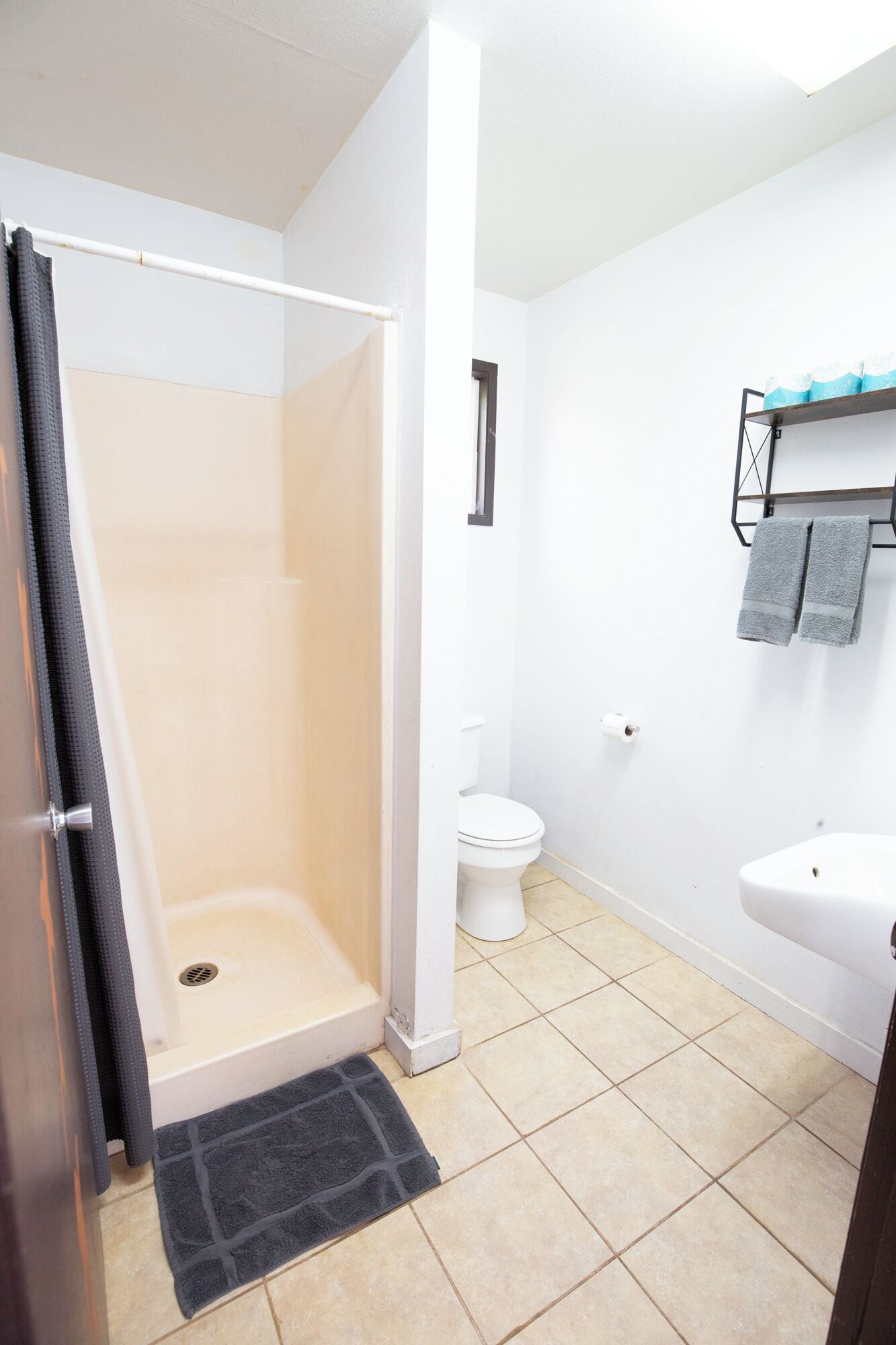 A bathroom with a shower, toilet, sink, and towel rack.