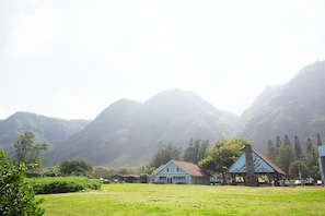 Ein Haus mit Veranda und Picknicktisch in einer grünen Wiese, im Hintergrund Berge.