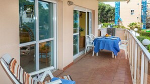 Un balcón con sillas y mesa blancos, listo para comer, con vista a una zona residencial.