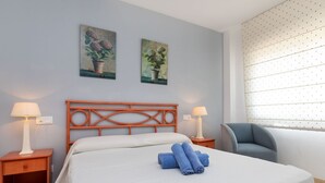 Ein Hotelzimmer mit einem Bett, zwei Nachttischen, einem Sessel und zwei Wandbildern.