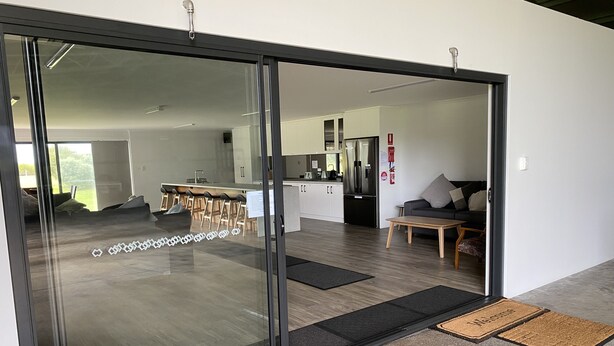 Een modern interieur met een glazen deur die leidt naar een woon-, keuken- en eetruimte.
