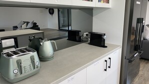 Een moderne keuken met een roestvrijstalen koelkast, een koffiezetapparaat, een waterkoker en een broodrooster.