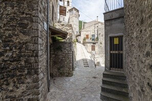 A narrow stone street with a staircase leading to a building with a barred window. - Belvilla by OYO Polino IV Novembre (Umbria)