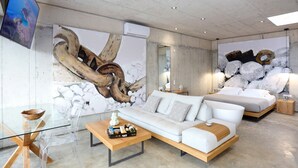 Uma sala de estar moderna com sofá, mesa de centro e uma grande obra de arte abstrata na parede.