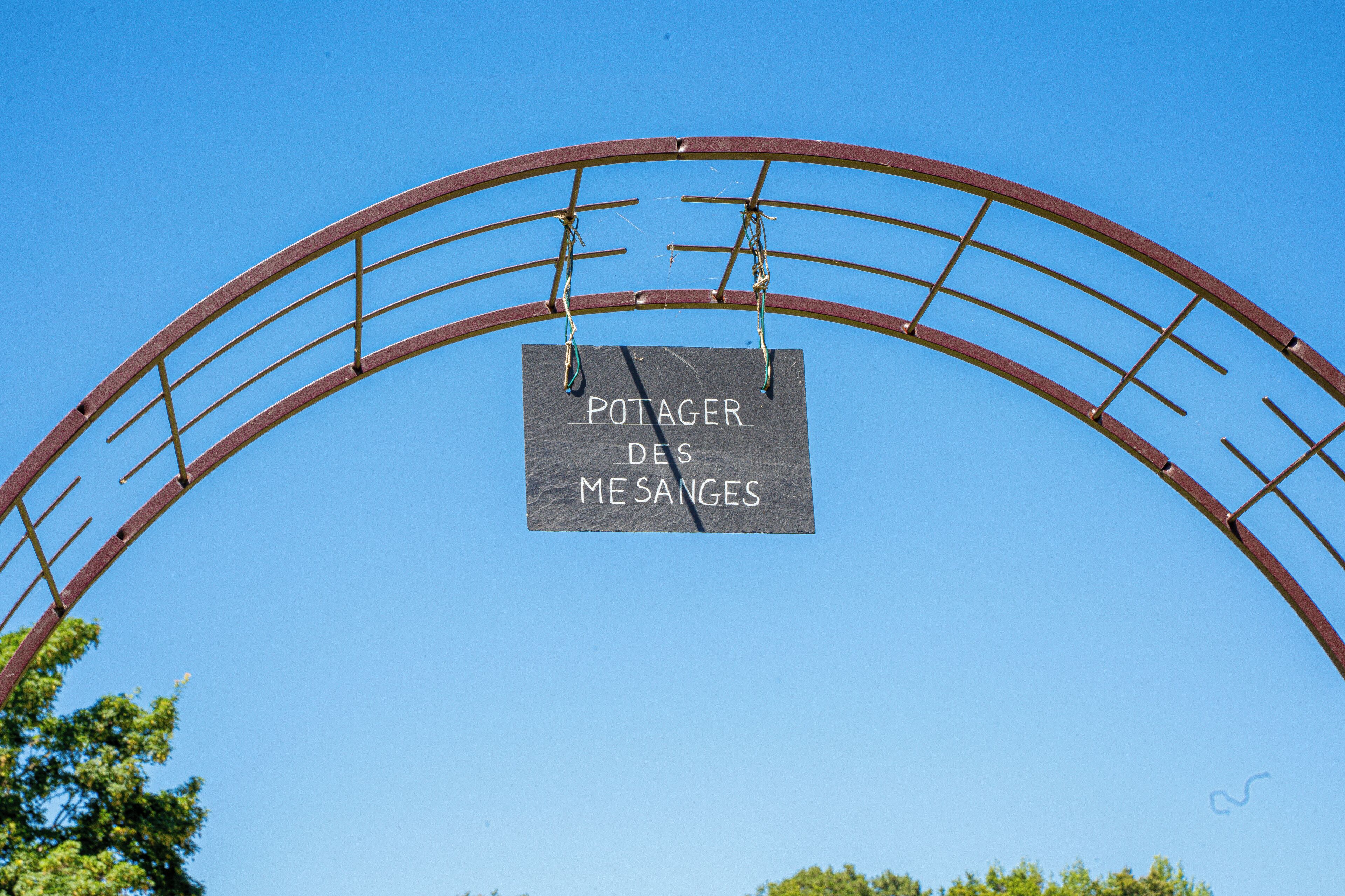 A metal archway with a sign that reads "POTAGER DES MESANGES".