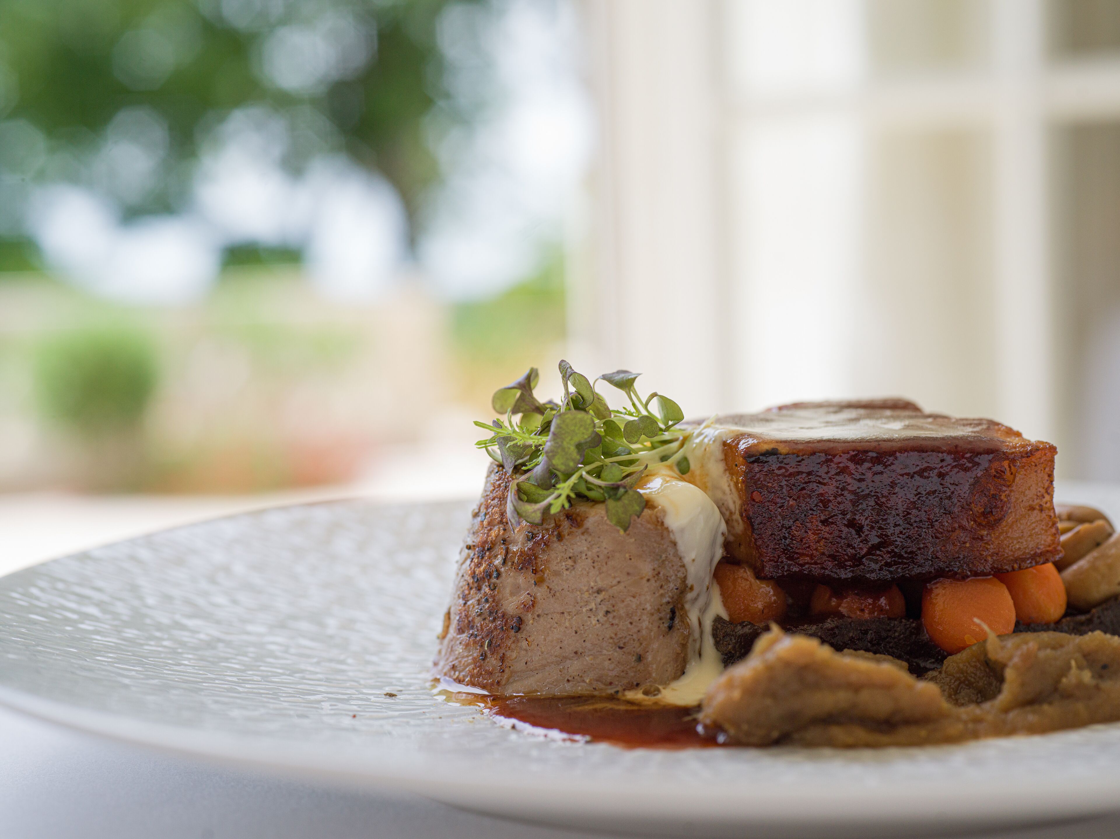 A plated dish with meat, vegetables, and a garnish.